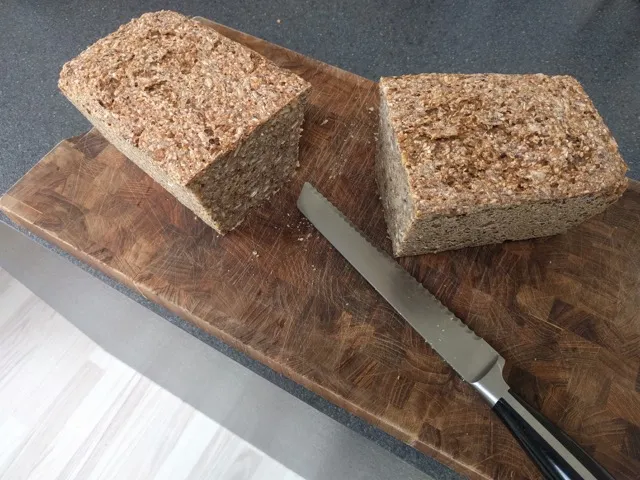 Det lækre rugbrød delt i 2 på er skærebradt af træ.